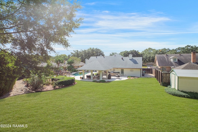 view of yard with a pool, a shed, and a patio area