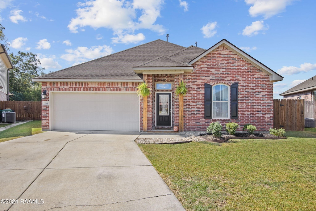 view of front of home with a front lawn, central AC unit, and a garage