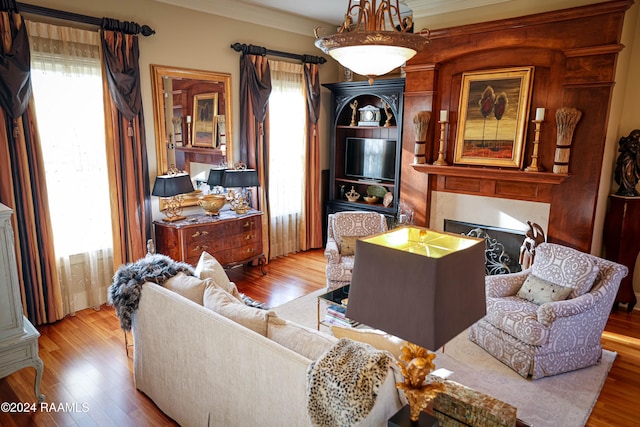 living room featuring light wood-type flooring, crown molding, and plenty of natural light