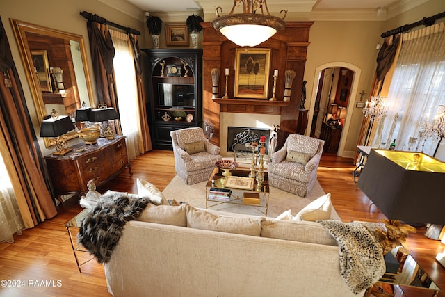 living room featuring ornamental molding, a fireplace, and light wood-type flooring