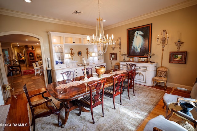 dining room with arched walkways, crown molding, wood finished floors, a chandelier, and recessed lighting