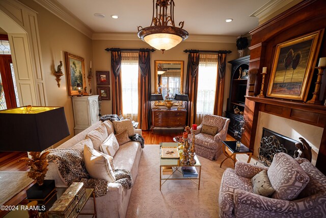 living room with a fireplace, healthy amount of natural light, crown molding, wood finished floors, and recessed lighting