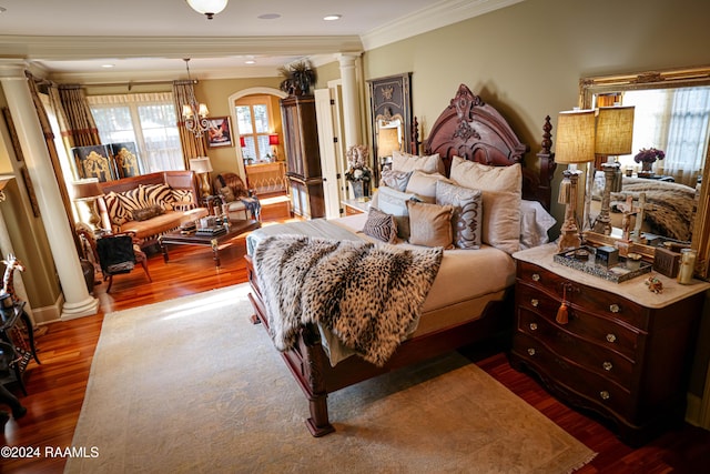 bedroom featuring ornate columns, wood-type flooring, ornamental molding, and an inviting chandelier