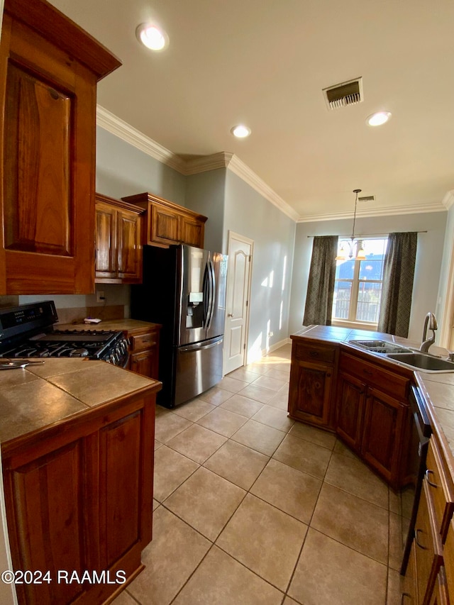 kitchen with tile countertops, hanging light fixtures, stainless steel appliances, sink, and crown molding