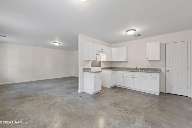 kitchen with concrete flooring, sink, and white cabinets