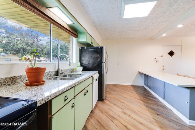 kitchen featuring black electric range oven, stainless steel fridge, sink, light wood-type flooring, and light stone counters