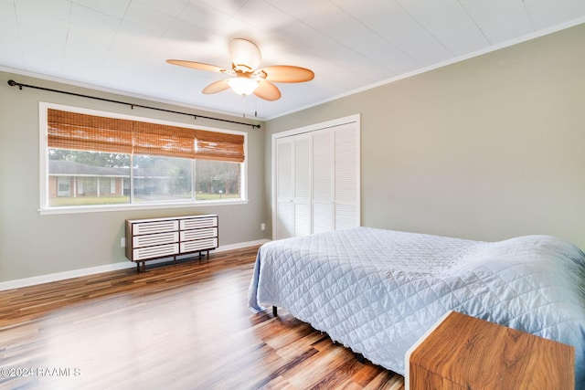 bedroom featuring crown molding, hardwood / wood-style flooring, a closet, and ceiling fan