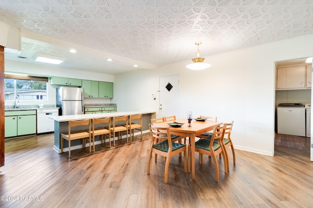 dining area featuring a textured ceiling, washing machine and dryer, sink, and light wood-type flooring