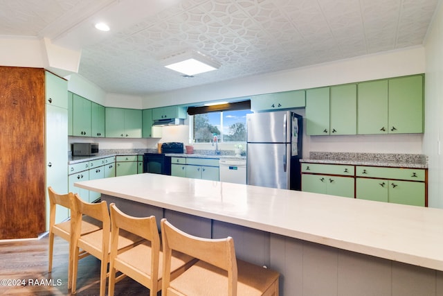 kitchen featuring appliances with stainless steel finishes, green cabinetry, a kitchen breakfast bar, and dark hardwood / wood-style flooring