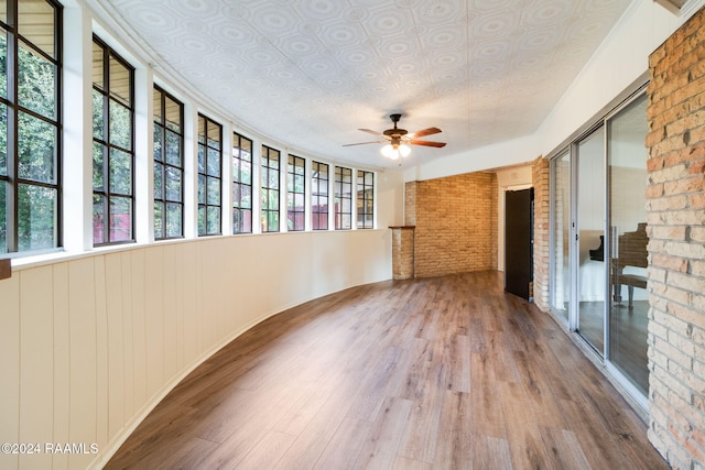 empty room featuring ceiling fan, brick wall, and hardwood / wood-style floors