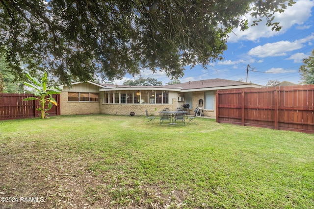 rear view of property with a lawn and a sunroom