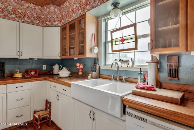 kitchen with tasteful backsplash, white cabinetry, sink, and dishwashing machine