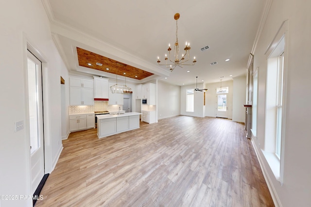 kitchen with a kitchen island with sink, open floor plan, light countertops, and decorative light fixtures