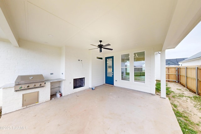 view of patio featuring ceiling fan, fence, grilling area, and exterior kitchen