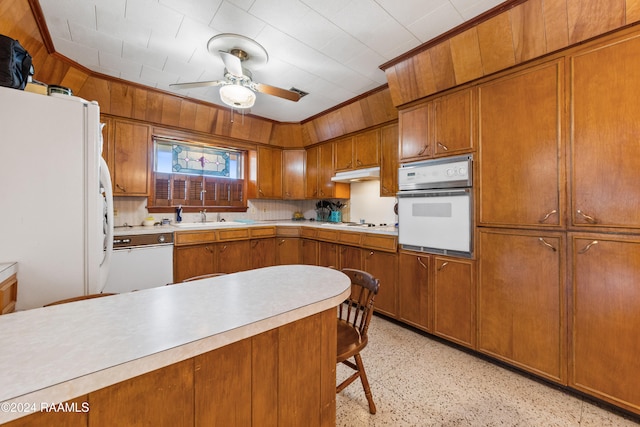 kitchen featuring a kitchen breakfast bar, white appliances, ceiling fan, and sink