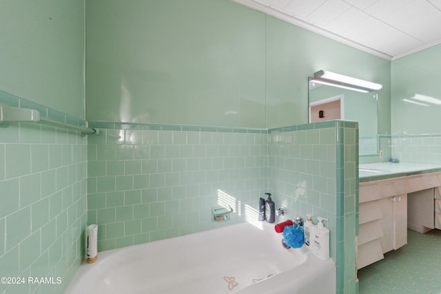 bathroom featuring a bath, vanity, tile walls, and ornamental molding