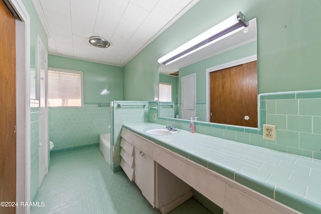 bathroom with a washtub, crown molding, toilet, vanity, and tile walls