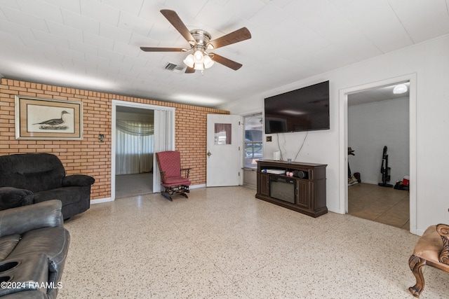 living room with ceiling fan and brick wall