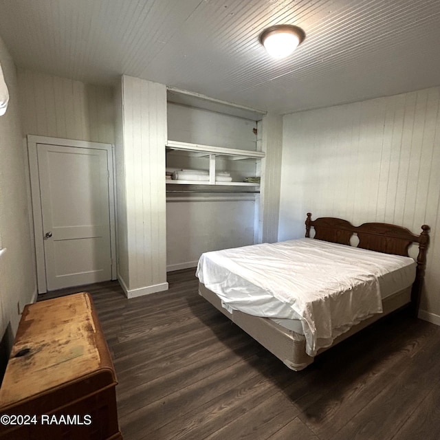 bedroom with dark wood-type flooring and wooden walls