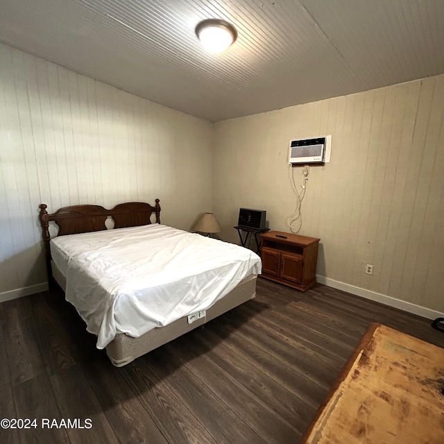 bedroom featuring a wall unit AC, dark hardwood / wood-style floors, and wooden walls