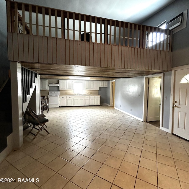 unfurnished living room with a towering ceiling, sink, and light tile patterned floors