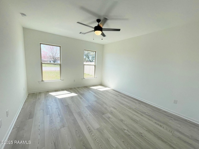 empty room featuring baseboards, visible vents, light wood finished floors, and ceiling fan