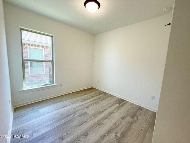 spare room featuring baseboards and wood finished floors