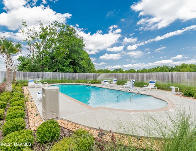 community pool with a patio area and fence