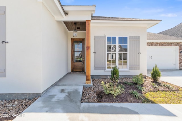 entrance to property with concrete driveway, a garage, and a shingled roof