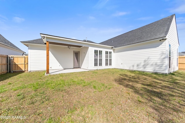 back of house featuring a lawn, a ceiling fan, and fence