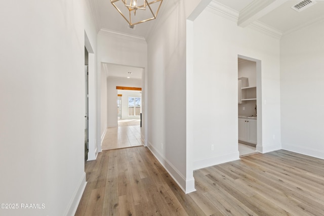 corridor featuring light wood-type flooring, visible vents, baseboards, and crown molding