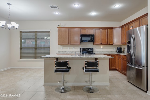 kitchen with black appliances, hanging light fixtures, sink, and an island with sink