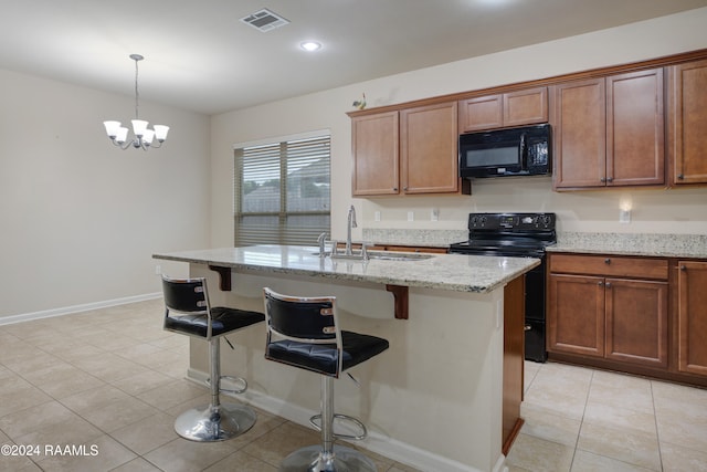 kitchen with sink, black appliances, an island with sink, and hanging light fixtures