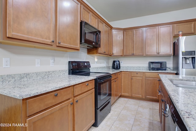 kitchen with black appliances, light stone counters, and light tile patterned floors