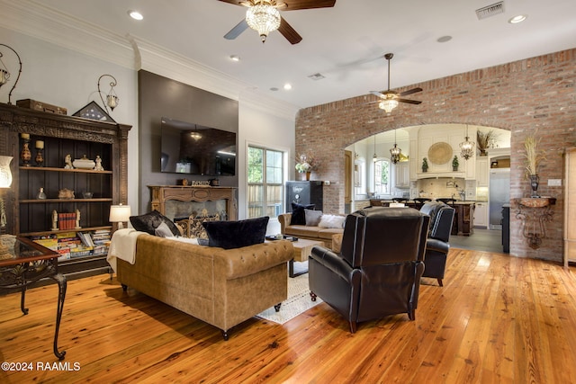 living room with brick wall, wood-type flooring, ceiling fan, and crown molding