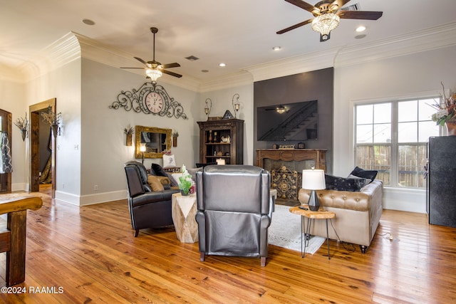 living room featuring light hardwood / wood-style flooring, ceiling fan, and crown molding