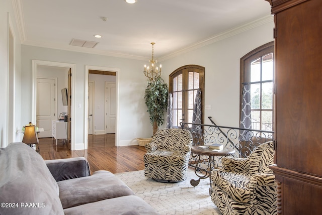 living room with ornamental molding, hardwood / wood-style flooring, and an inviting chandelier