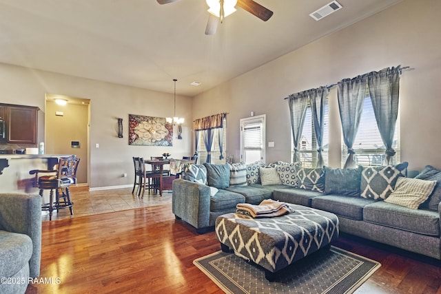 living room with ceiling fan with notable chandelier and hardwood / wood-style flooring