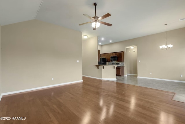 unfurnished living room featuring dark wood-type flooring, lofted ceiling, and ceiling fan with notable chandelier