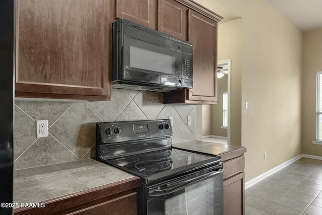 kitchen with a wealth of natural light, black appliances, light tile patterned flooring, and decorative backsplash