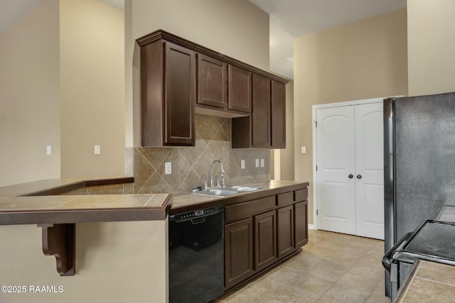 kitchen with dark brown cabinets, sink, black appliances, and backsplash