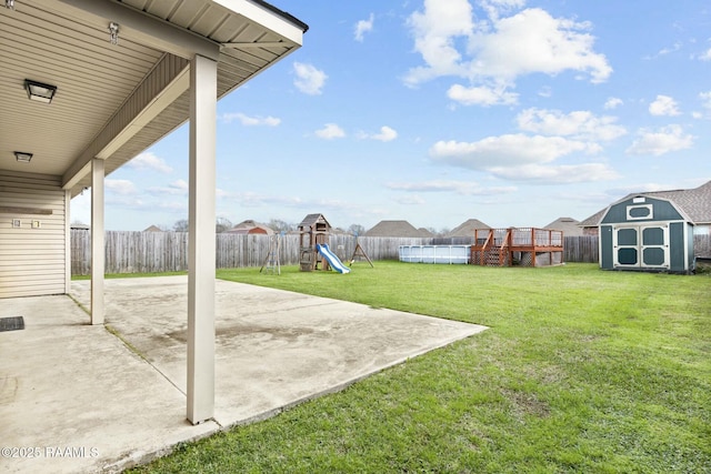 view of yard featuring a playground, a storage unit, a patio area, and a pool