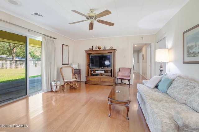 living room with light hardwood / wood-style floors, ornamental molding, and ceiling fan