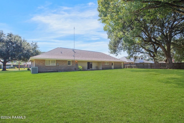 rear view of house featuring a lawn and central AC unit