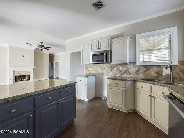 kitchen with appliances with stainless steel finishes, backsplash, dark stone counters, ceiling fan, and sink