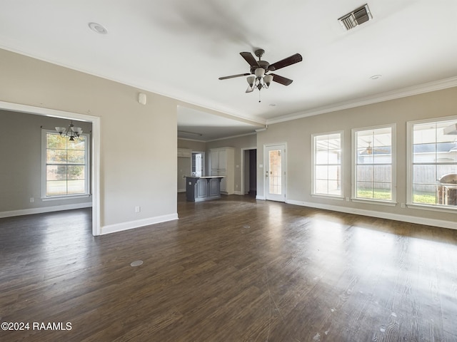 unfurnished living room with ceiling fan with notable chandelier, dark hardwood / wood-style flooring, plenty of natural light, and ornamental molding