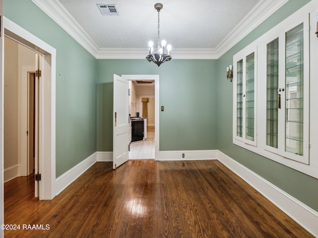 empty room featuring hardwood / wood-style floors, a textured ceiling, crown molding, and an inviting chandelier