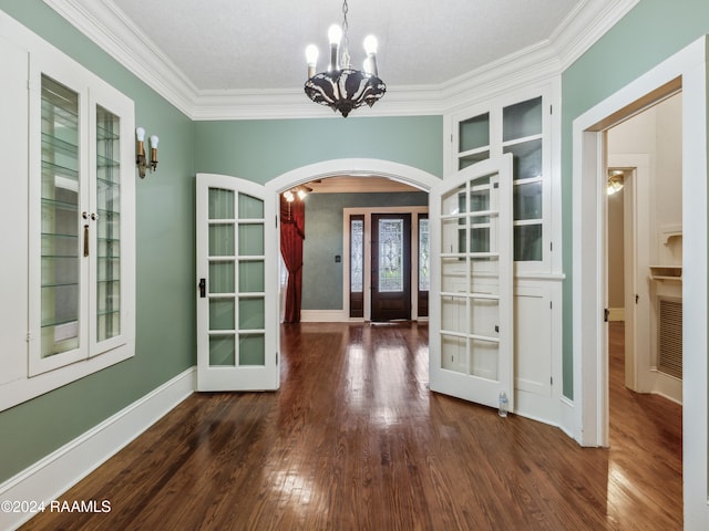 unfurnished dining area featuring french doors, a textured ceiling, dark hardwood / wood-style flooring, and ornamental molding