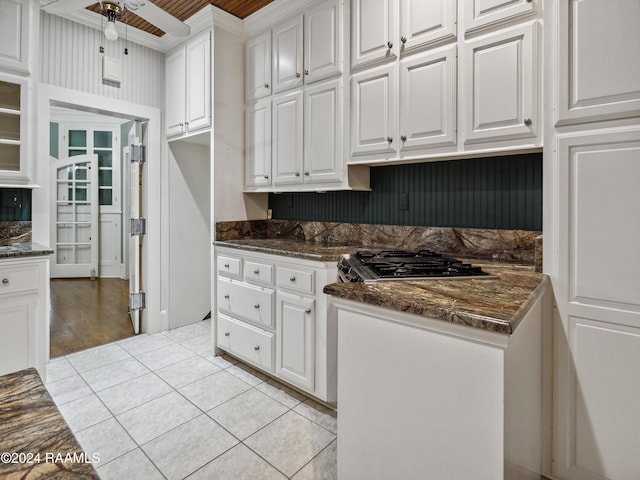 243 W Grolee St, Opelousas, LA 70570 - kitchen featuring white cabinets, stainless steel gas cooktop, a ceiling fan, light tile patterned floors, and dark stone counters