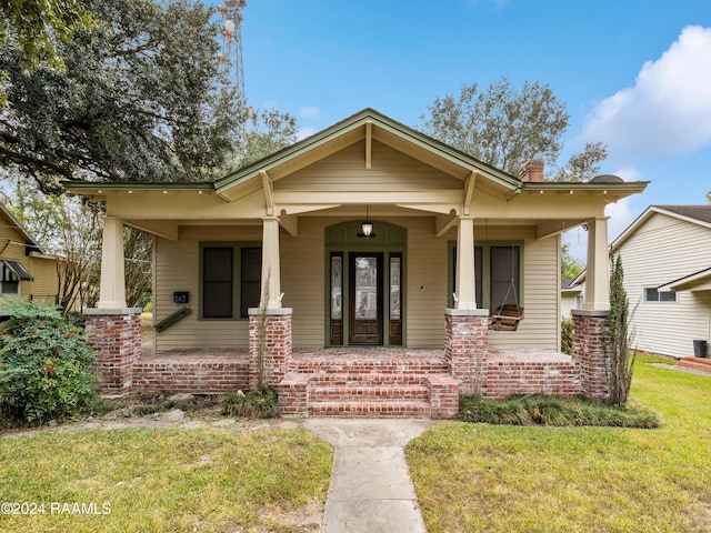 243 W Grolee St, Opelousas, LA 70570 - view of front of home with covered porch, a front yard, and a chimney
